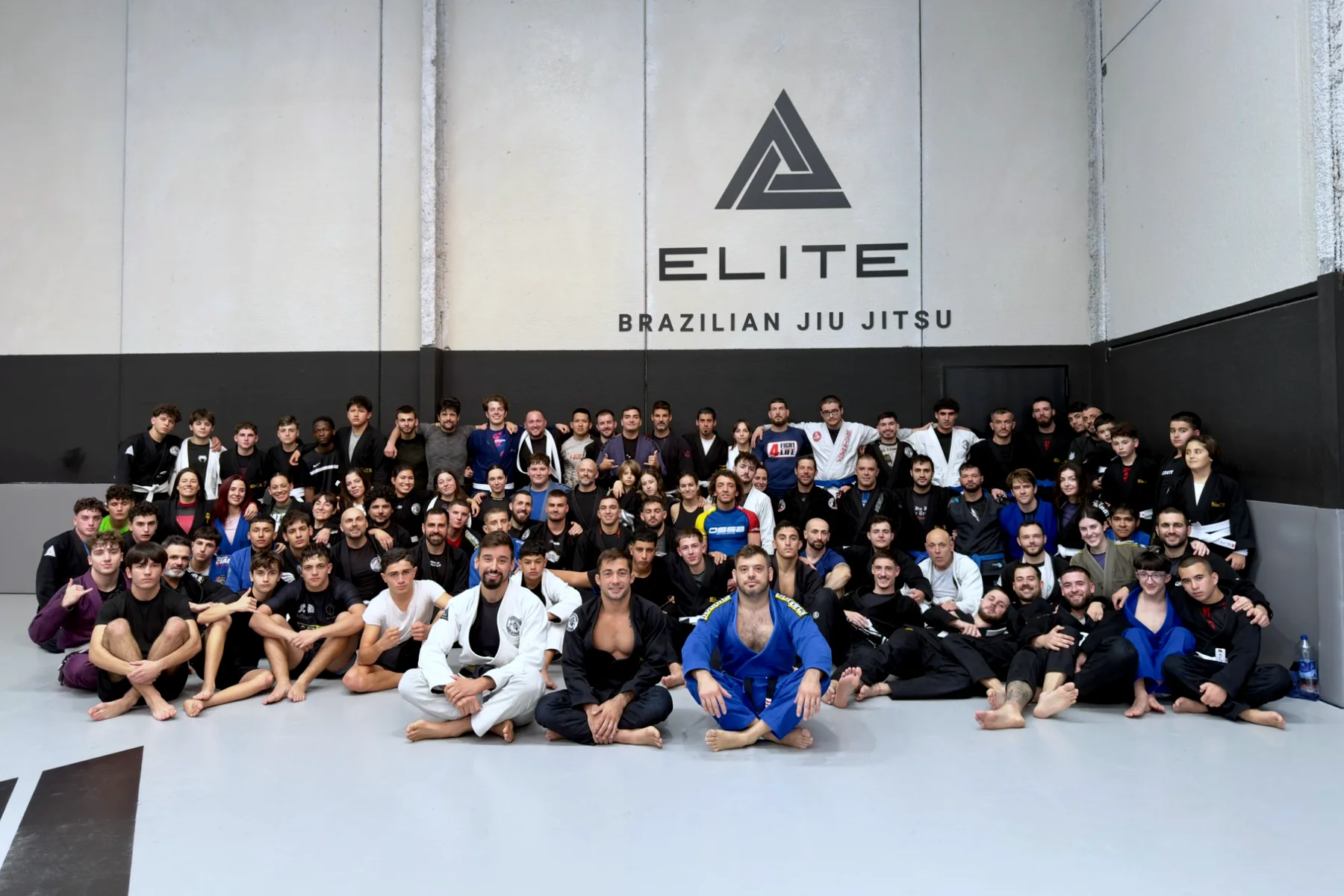 Alumnos y profesores de Elite BJJ reunidos en el tatami de la escuela, en Torrent, delante del logo
