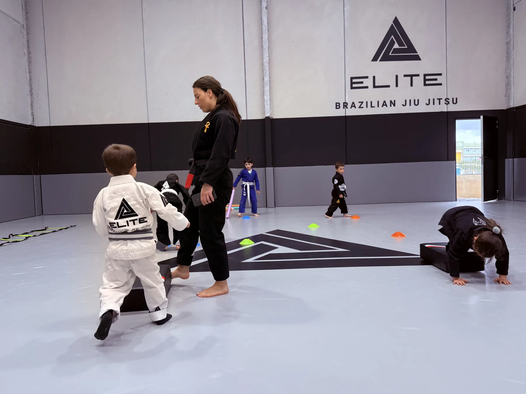 La profesora Stephanie con niños de 3 a 5 años en el tatami de Elite BJJ, Torrent