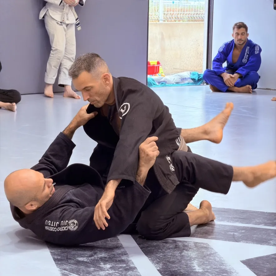 El maestro Cícero Costha entrenando en el suelo con un cinturón negro durante el seminario de los tres años de Elite BJJ