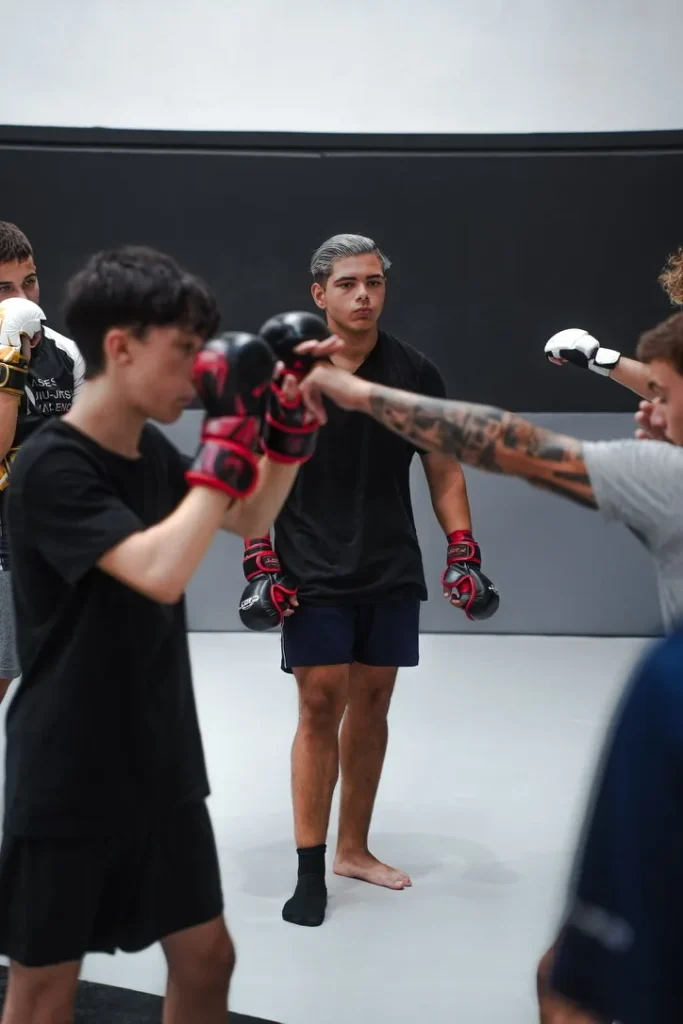 Alumno de la clase de MMA de Elite BJJ con guantes, preparado para el trabajo por parejas