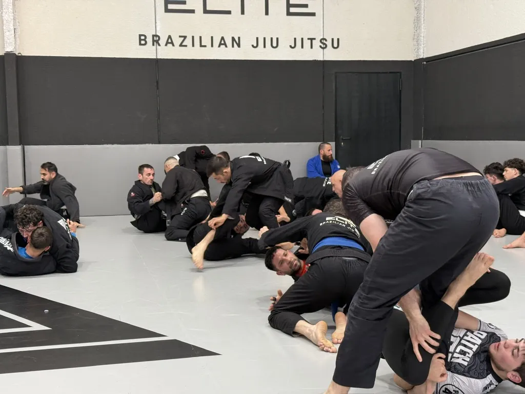 Alumnos de Elite BJJ entrenando en el suelo con kimono durante la clase