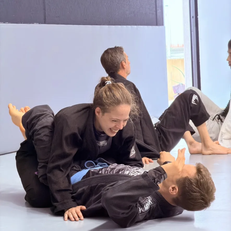 Una alumna de Elite BJJ sonríe mientras entrena con un compañero durante el seminario