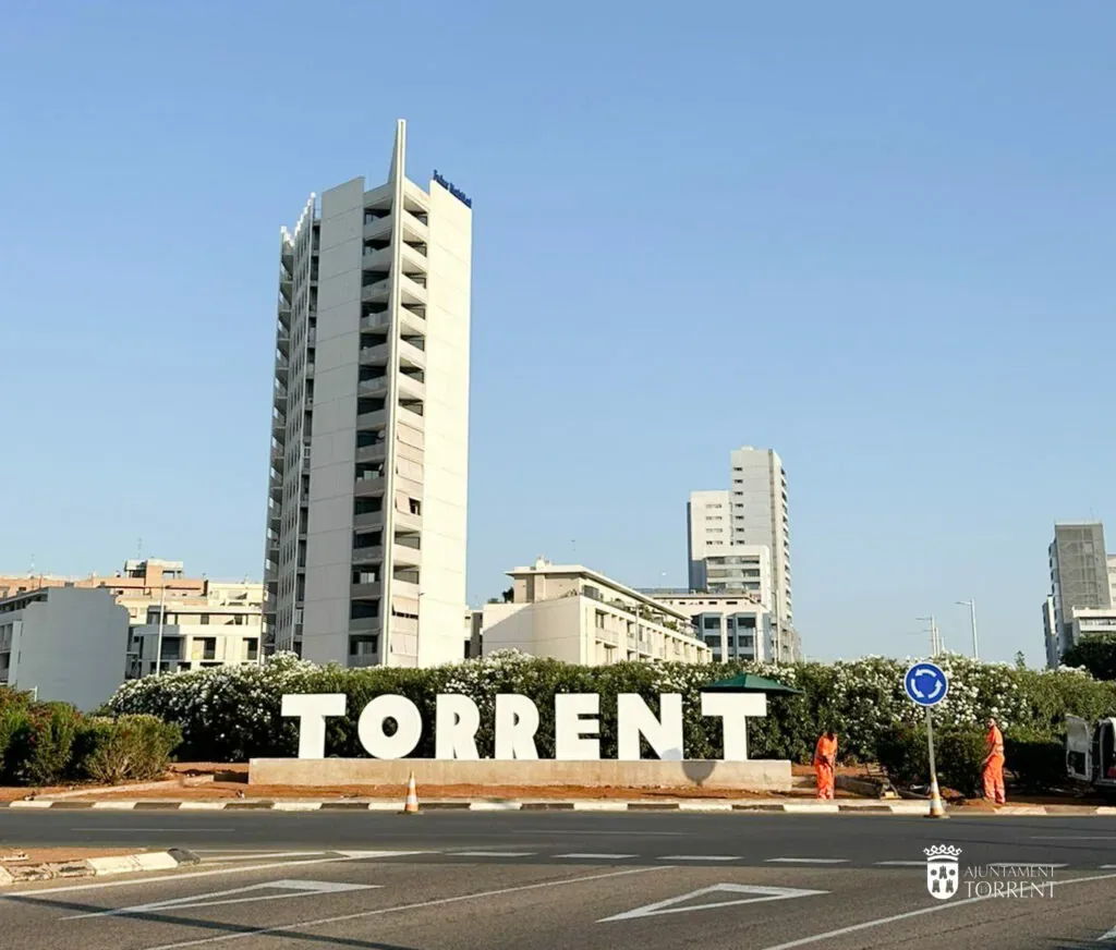 Letras de Torrent en una rotonda de la ciudad, con edificios altos al fondo